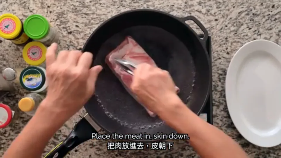 Placing the pork belly skin-side down into boiling water in a wok