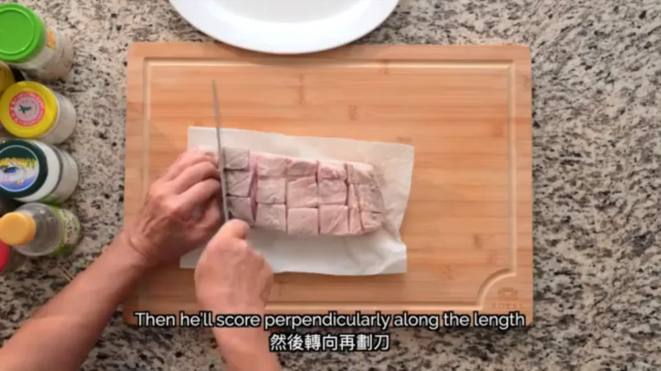 Scoring the meat side of the pork belly into a grid of squares with a cleaver