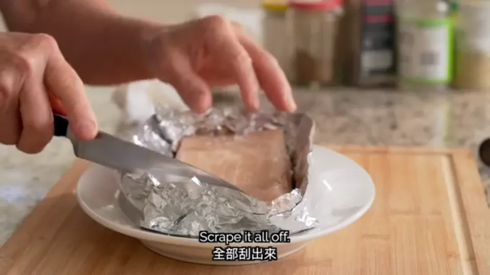 Scraping the damp salt off the surface of the pork skin with a cleaver blade