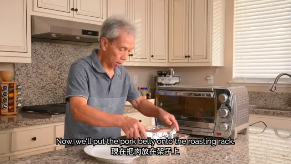 Setting the foil-wrapped pork belly on a wire rack over a water-filled baking pan