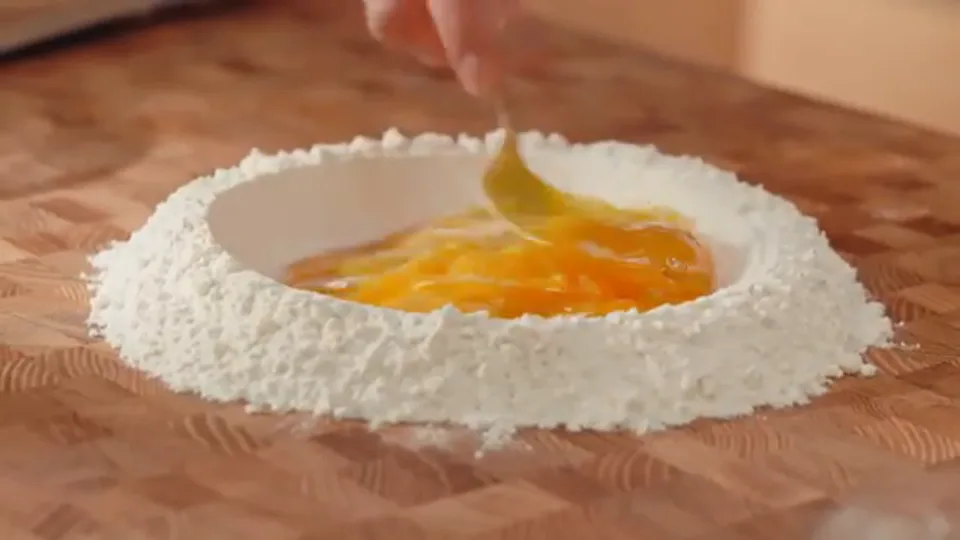 Whisking eggs in the center of the flour well