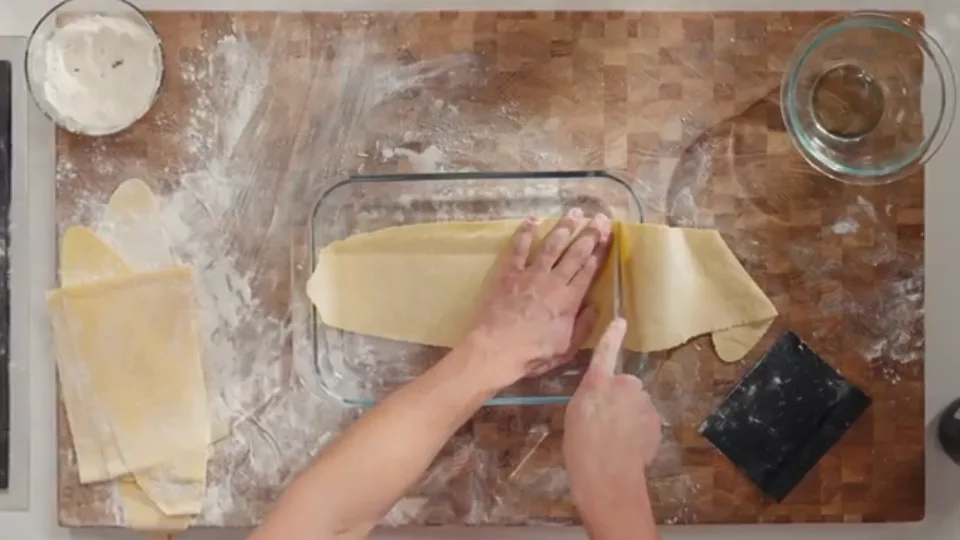 Tracing and trimming pasta sheets against baking dish