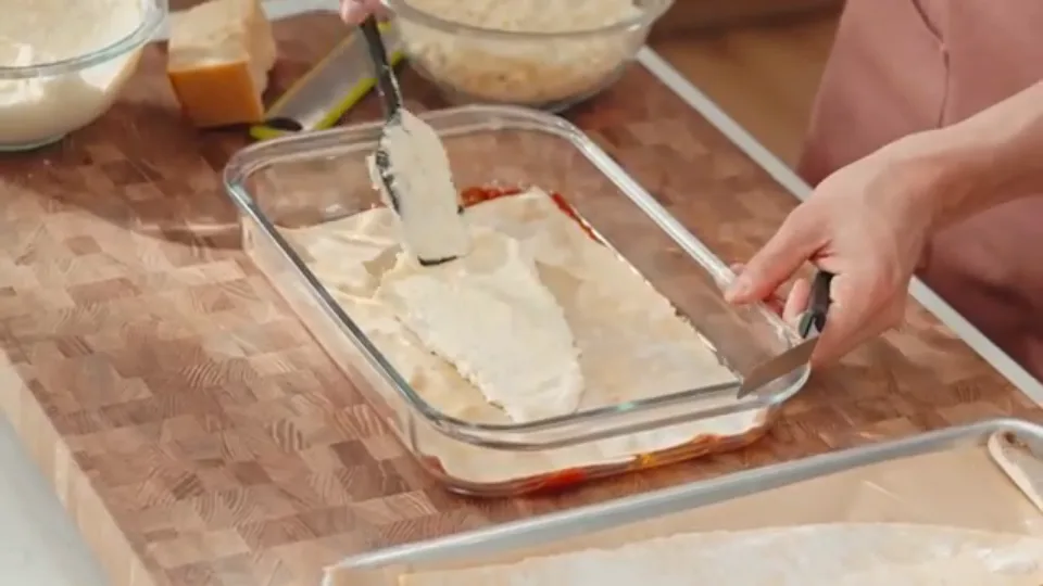 Spreading ricotta filling evenly over fresh pasta layer using offset spatula