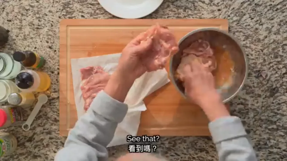 Holding the dried chicken thigh and placing it meat-side down into marinade