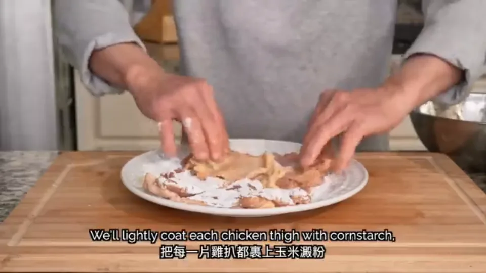 Dredging the chicken thigh on a plate covered with cornstarch