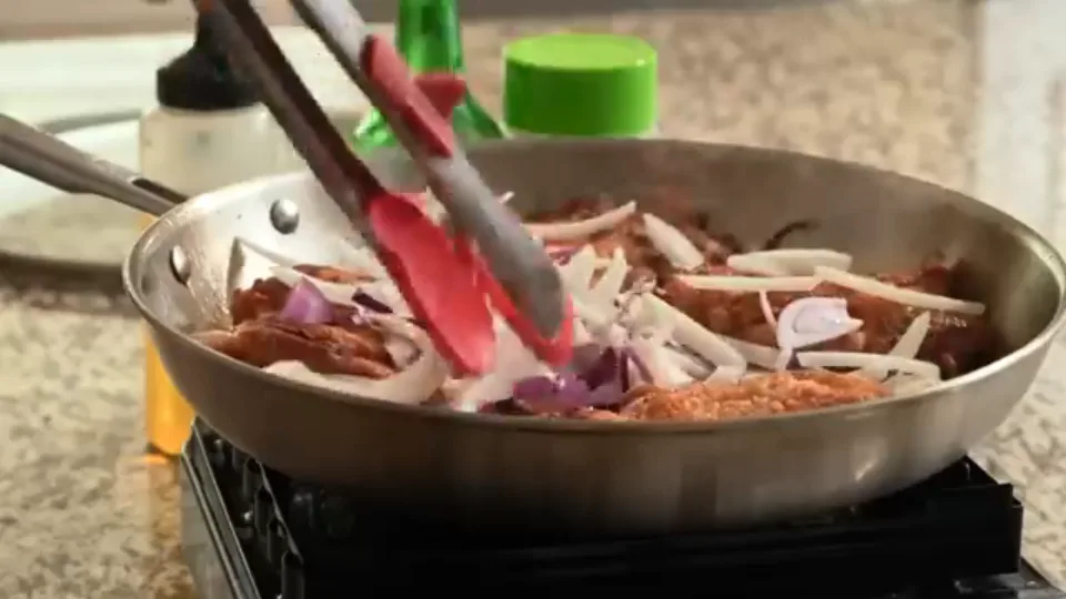 Adding sliced onions and garlic to the skillet and pouring Shaoxing wine